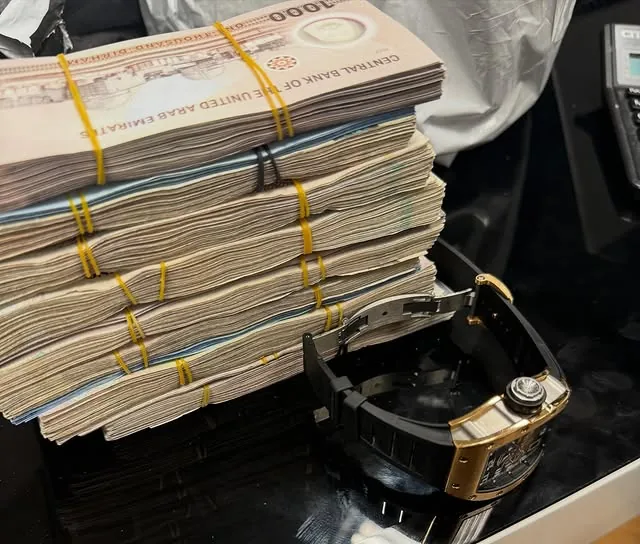 Stacked AED notes alongside a Richard Mille watch